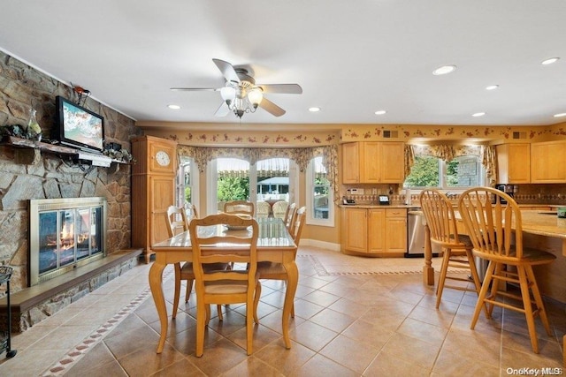 tiled dining space with ceiling fan, a fireplace, and a healthy amount of sunlight