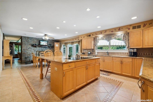 kitchen with ceiling fan, sink, black electric stovetop, a center island with sink, and light tile patterned flooring