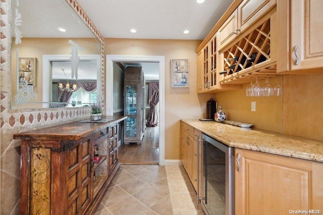 bar featuring light stone countertops, light tile patterned floors, beverage cooler, and a notable chandelier