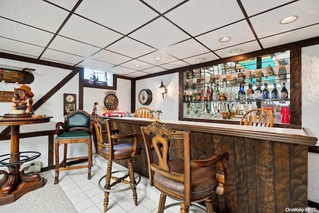 bar with a paneled ceiling and light tile patterned floors