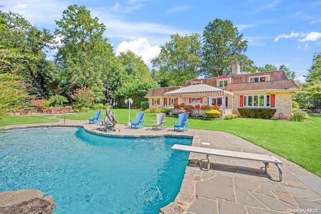 view of swimming pool with a lawn, a diving board, and a patio