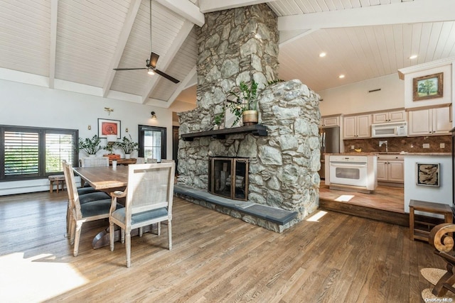 dining space with a fireplace, light hardwood / wood-style floors, high vaulted ceiling, and ceiling fan