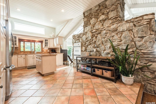 kitchen featuring stainless steel fridge, a center island, light tile patterned floors, and cream cabinets