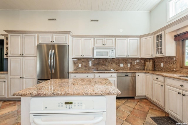 kitchen with light stone countertops, backsplash, and appliances with stainless steel finishes