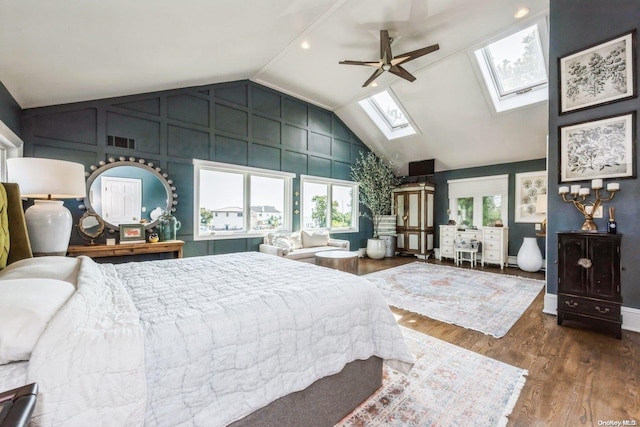 bedroom featuring ceiling fan, wood-type flooring, and lofted ceiling with skylight