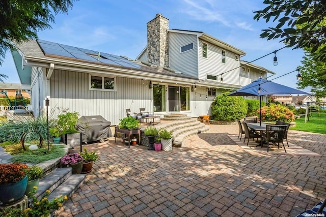 back of property featuring a patio and solar panels