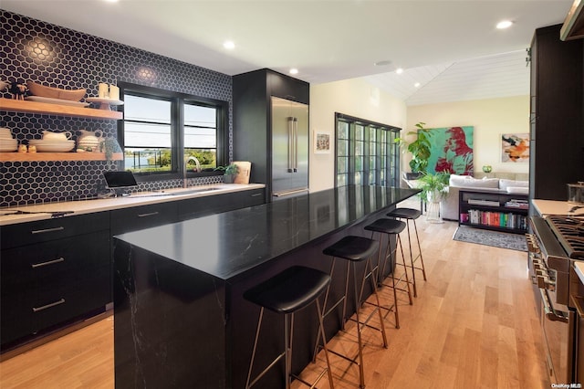 kitchen with a breakfast bar area, tasteful backsplash, a kitchen island, and light wood-type flooring