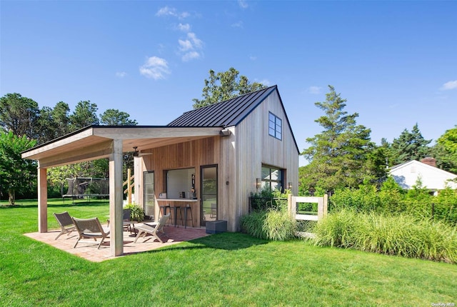 back of property with exterior bar, a yard, a patio, and a trampoline