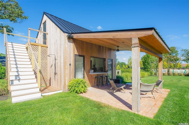 exterior space featuring a lawn, an outdoor bar, and a patio