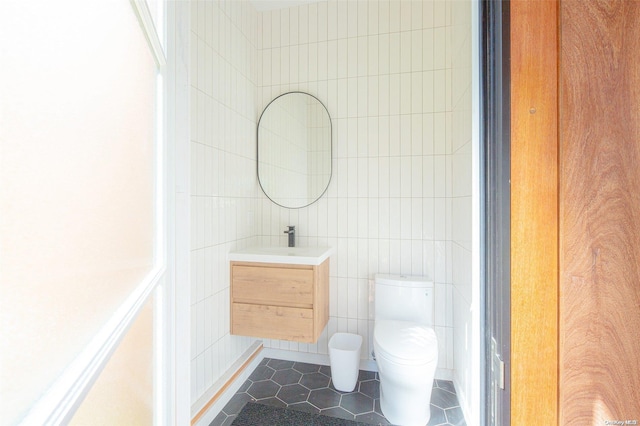 bathroom with tile patterned floors, vanity, tile walls, and toilet