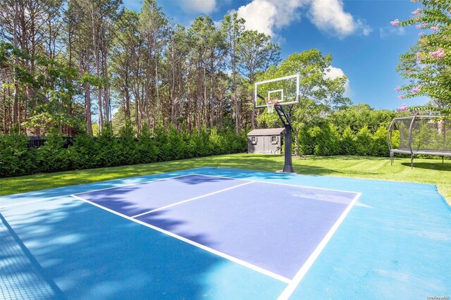 view of basketball court with a yard and a trampoline