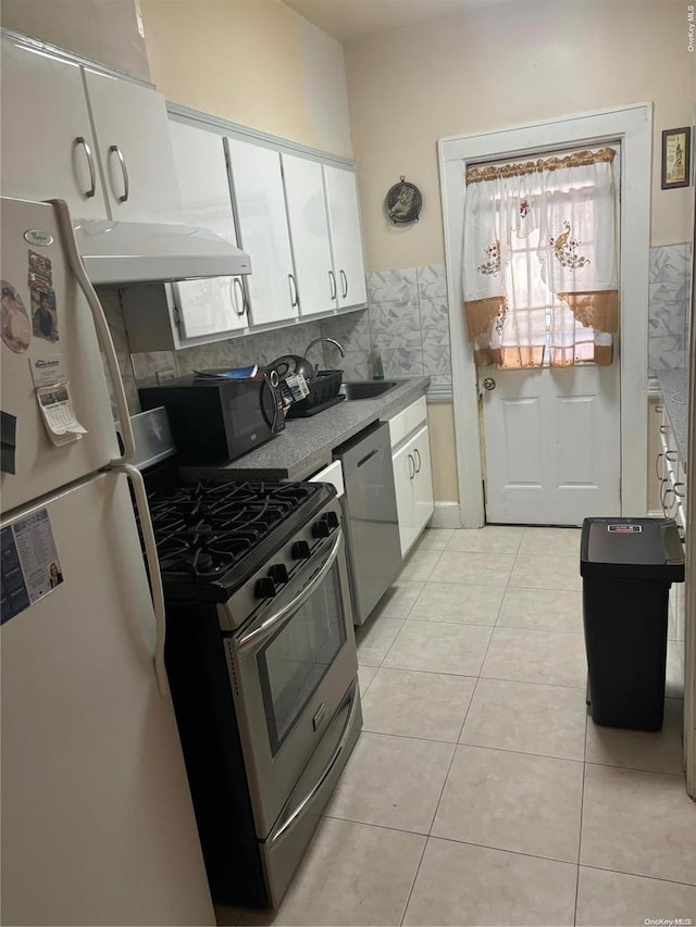 kitchen featuring white cabinetry, sink, tasteful backsplash, light tile patterned floors, and appliances with stainless steel finishes