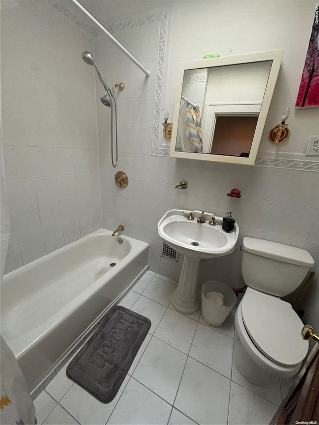 full bathroom with tile patterned floors, sink, tiled shower / bath, toilet, and tile walls