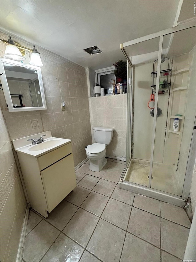 bathroom with toilet, vanity, tile patterned floors, and tile walls