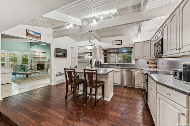 kitchen with backsplash, dark hardwood / wood-style floors, a center island, and appliances with stainless steel finishes