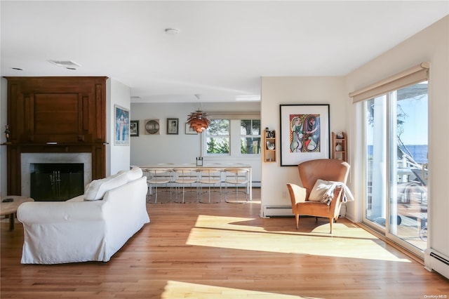 living room with light wood-type flooring, a baseboard radiator, and plenty of natural light