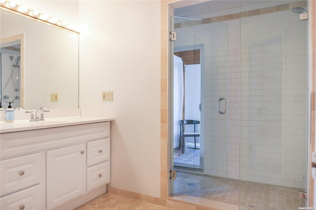 bathroom with tile patterned flooring, vanity, and walk in shower