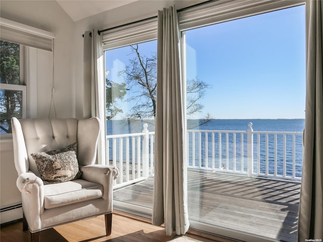 doorway to outside featuring a water view, a baseboard radiator, hardwood / wood-style flooring, and lofted ceiling