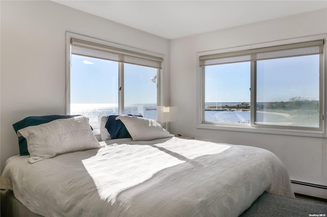 bedroom with a water view, multiple windows, and a baseboard heating unit