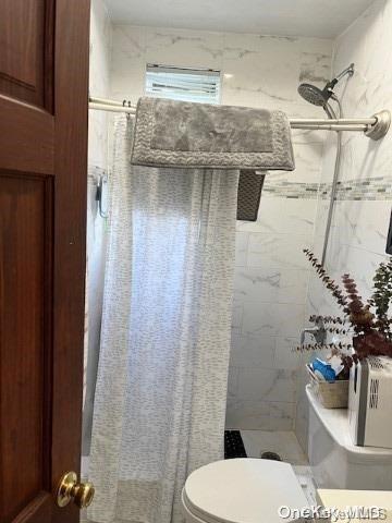 bathroom featuring toilet and tiled shower