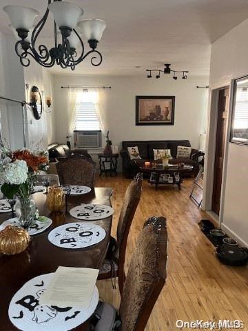 dining area featuring wood-type flooring, cooling unit, and a notable chandelier