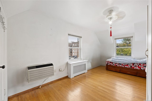 bedroom featuring ceiling fan, radiator heating unit, hardwood / wood-style floors, and vaulted ceiling