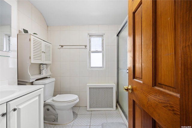 bathroom with tile patterned floors, an enclosed shower, vanity, tile walls, and radiator heating unit