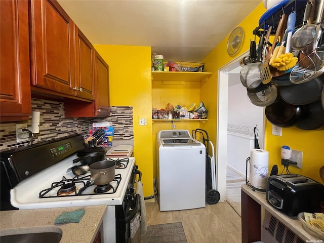 kitchen with backsplash, white gas range oven, and washer / dryer