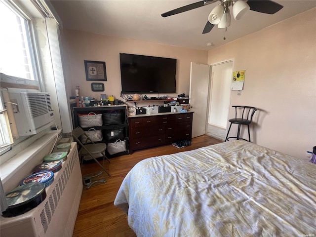 bedroom featuring radiator heating unit, hardwood / wood-style flooring, ceiling fan, and cooling unit