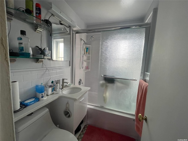 full bathroom with vanity, backsplash, toilet, and bath / shower combo with glass door