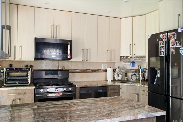 kitchen featuring cream cabinetry, sink, and black appliances