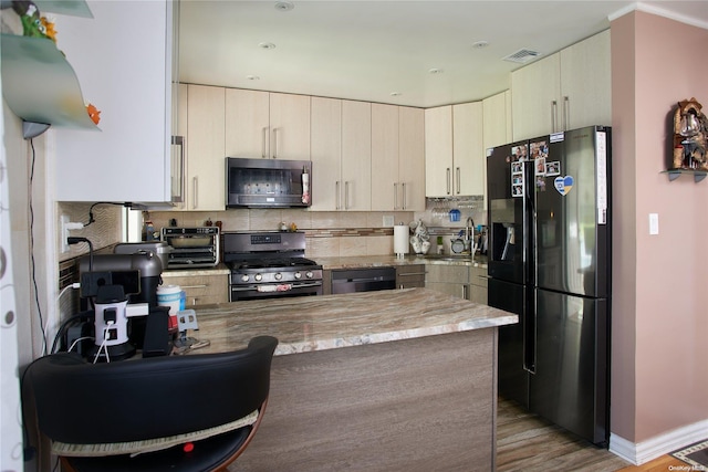 kitchen featuring kitchen peninsula, light wood-type flooring, sink, black appliances, and cream cabinets