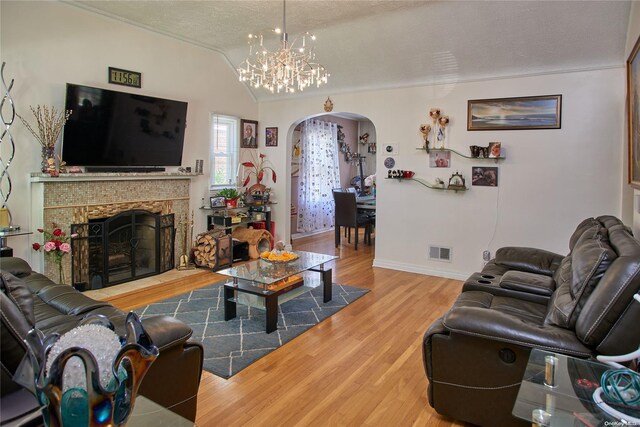 living room with hardwood / wood-style floors, a textured ceiling, an inviting chandelier, and lofted ceiling