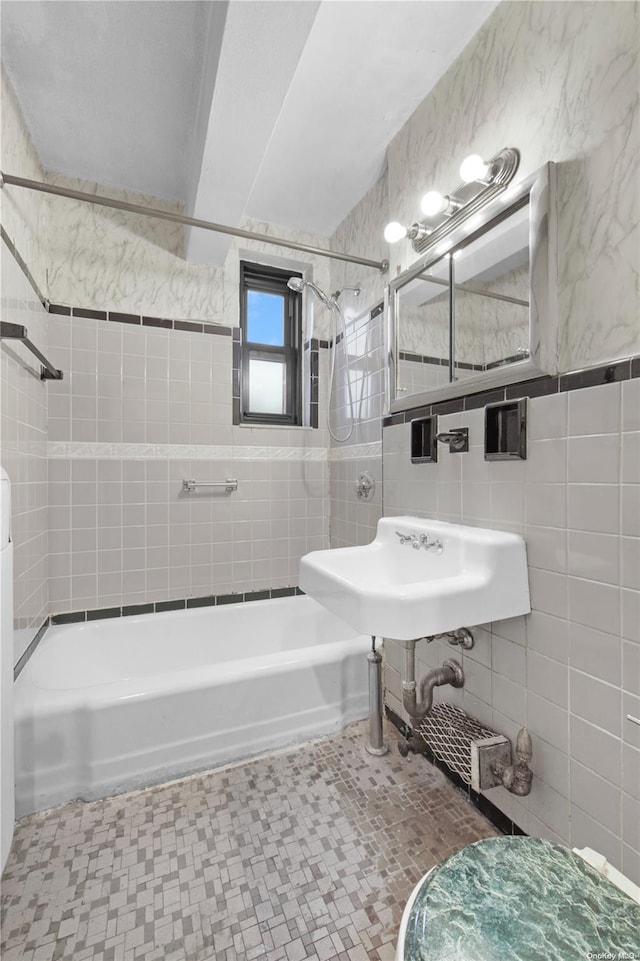 bathroom featuring tiled shower / bath combo, sink, and tile walls