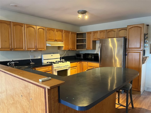 kitchen with white range with gas stovetop, sink, stainless steel fridge, light hardwood / wood-style floors, and kitchen peninsula