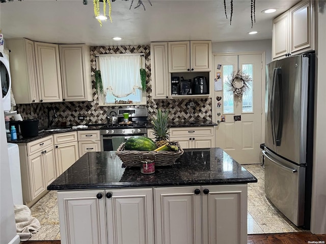 kitchen featuring appliances with stainless steel finishes, tasteful backsplash, sink, dark stone countertops, and a kitchen island