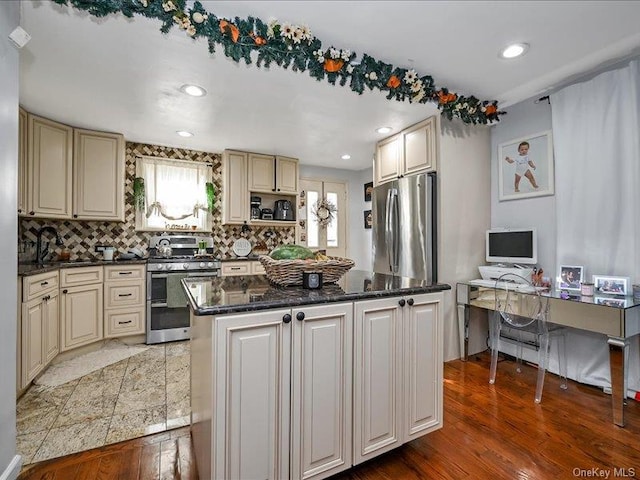 kitchen featuring a center island, sink, decorative backsplash, appliances with stainless steel finishes, and wood-type flooring