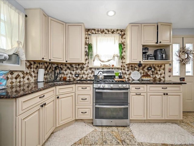 kitchen featuring cream cabinetry, stainless steel gas range oven, and sink