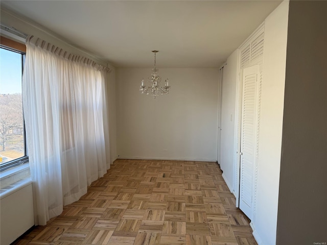 unfurnished dining area featuring an inviting chandelier and light parquet flooring