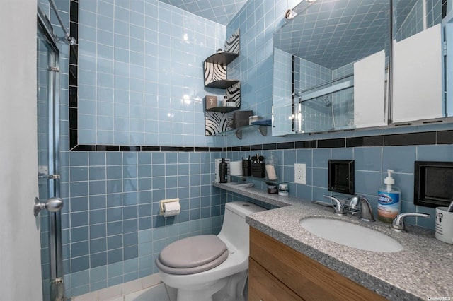 bathroom featuring toilet, vanity, tile patterned flooring, tile walls, and a shower with door