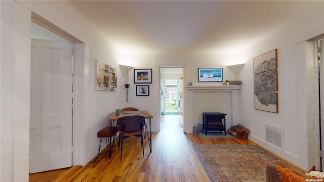 living room with light hardwood / wood-style floors, a wood stove, and crown molding