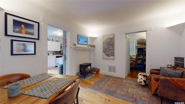 dining space with light hardwood / wood-style floors, a wood stove, and crown molding