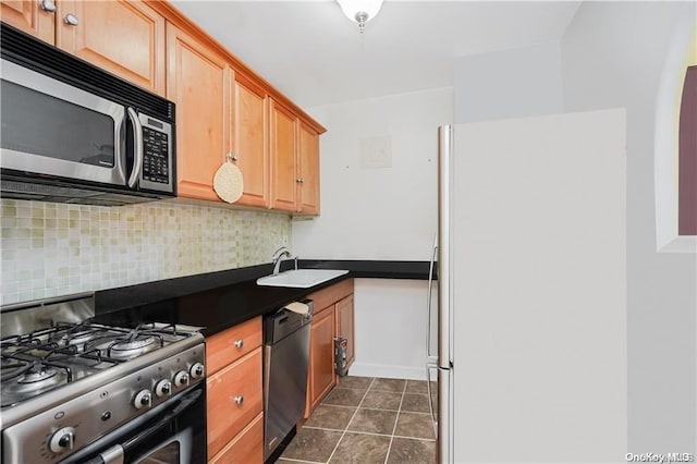 kitchen featuring appliances with stainless steel finishes, tasteful backsplash, dark tile patterned flooring, and sink