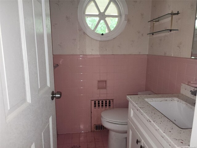 bathroom featuring vanity, tile walls, tile patterned flooring, radiator heating unit, and toilet