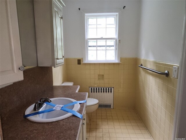 bathroom with vanity, toilet, tile walls, and radiator