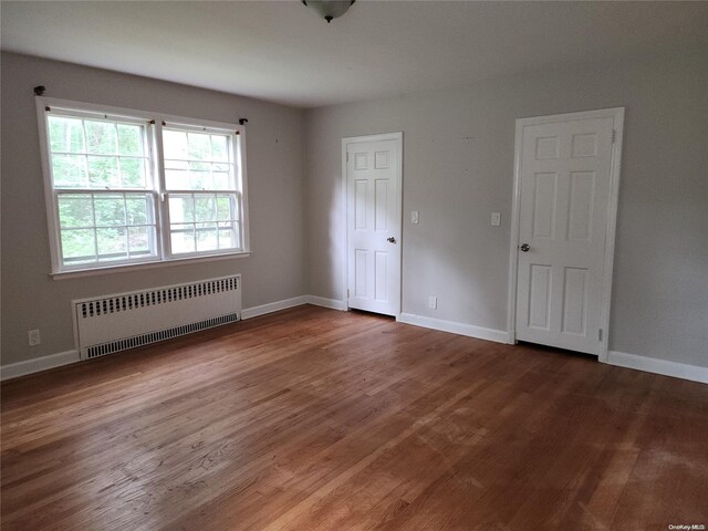 spare room featuring radiator and dark hardwood / wood-style floors