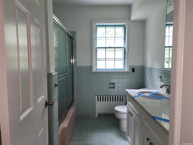 full bathroom featuring vanity, toilet, radiator heating unit, and tile walls