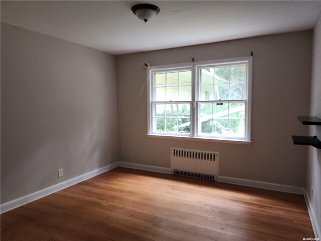 unfurnished room with radiator heating unit and wood-type flooring