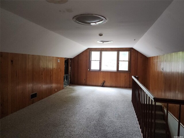 bonus room featuring wooden walls, carpet floors, and vaulted ceiling