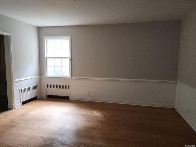 spare room featuring radiator heating unit and light hardwood / wood-style floors